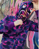 chłopak ubrany w bluzę bape shark w kolorze fioletowym na tle graffiti