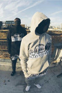 Dwóch modeli w bluzach Trapstar na dachu – szara bluza z dużym logo na pierwszym planie, czarna bluza w tle, klimat streetwear
